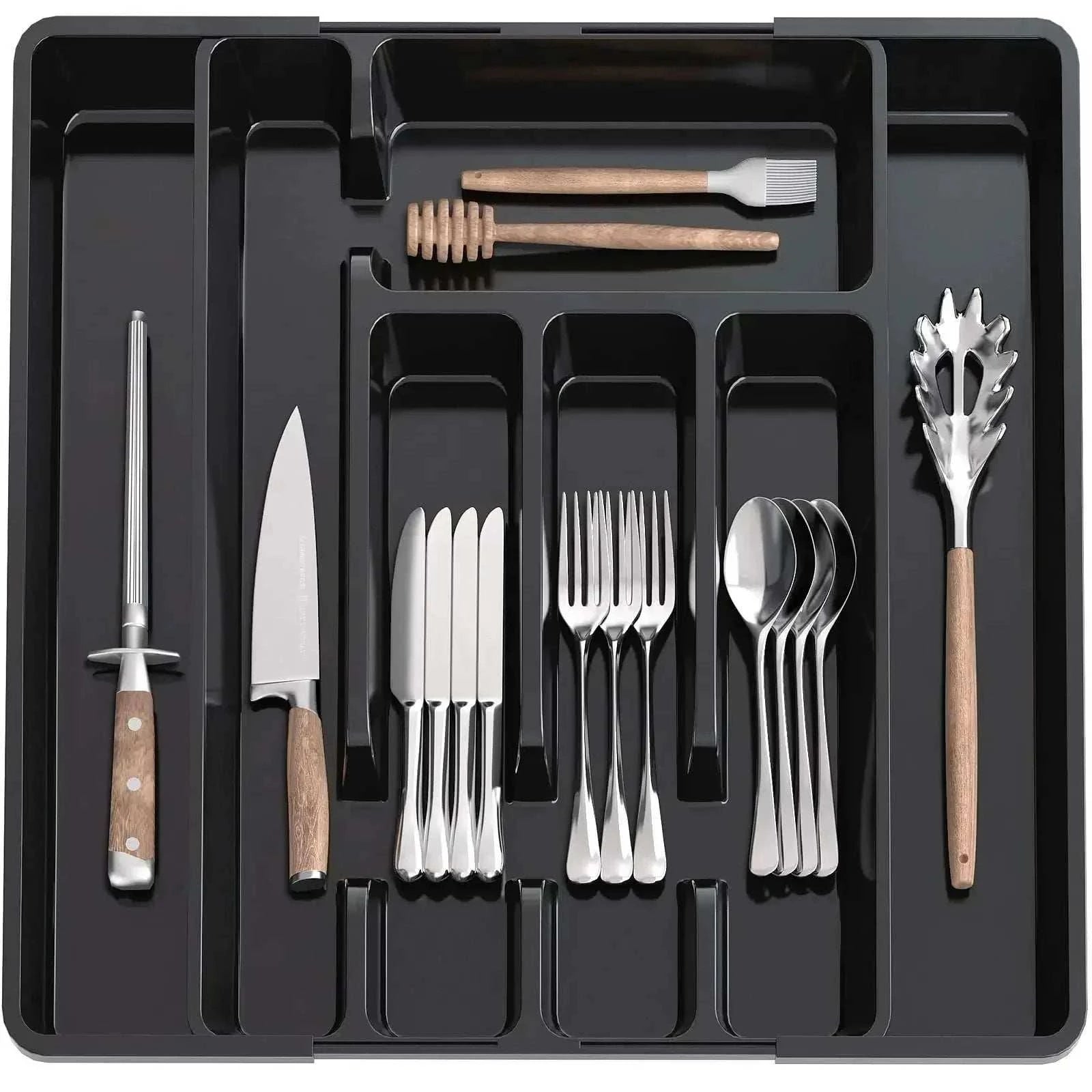 Adjustable pantry organizer utensil tray with compartments holding knives, forks, spoons, and kitchen tools in black plastic.